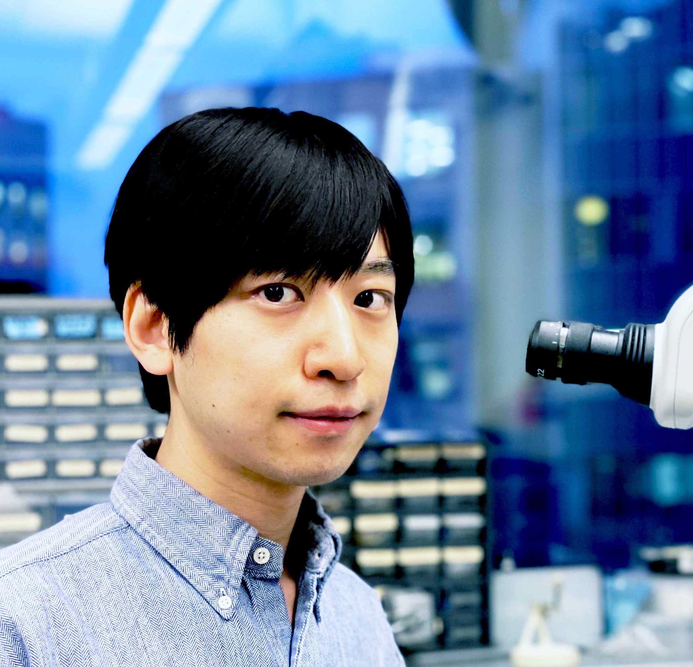 Takato Honda sits at the lab bench next to a microscope