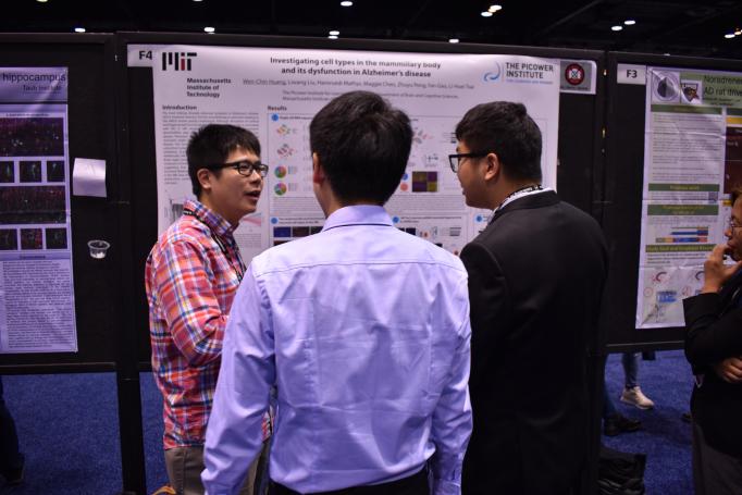 Wen-Chin Huang gestures as he presents his poster to two onlookers