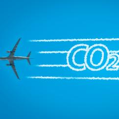 An airplaine seen  from below extends contrails that take the form of the letters CO2