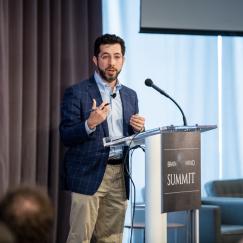 Ed Boyden stands and gestures at the podium of the Brain Mind Summit