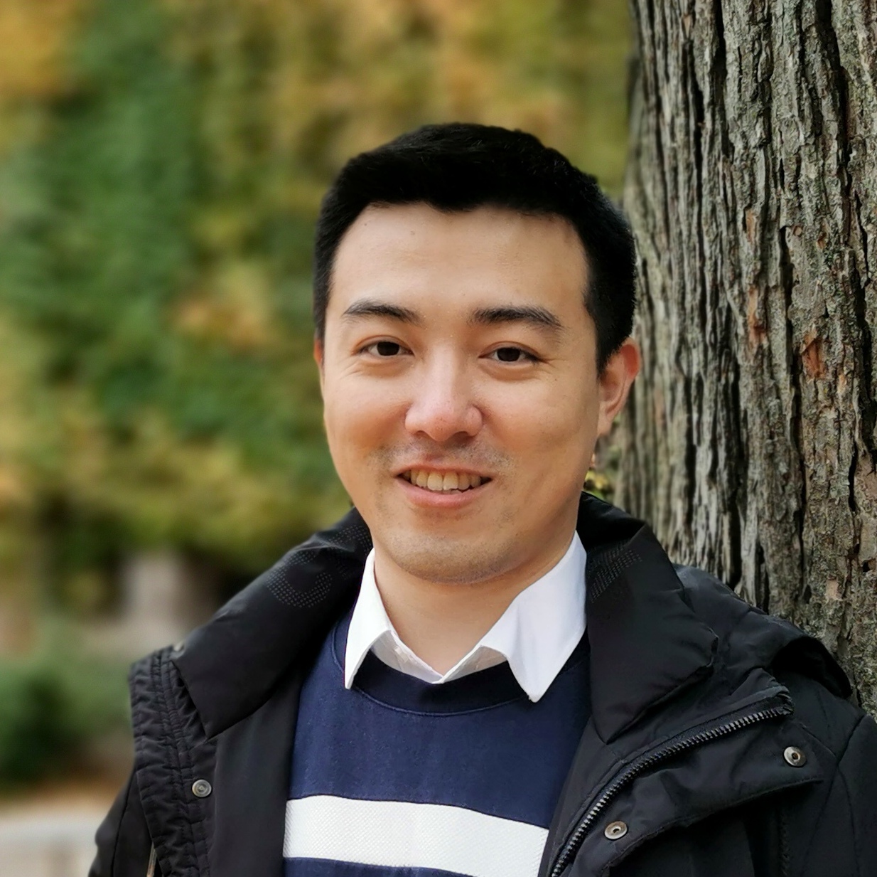 A portrait of Kailong Wen, standing outside next to a tree