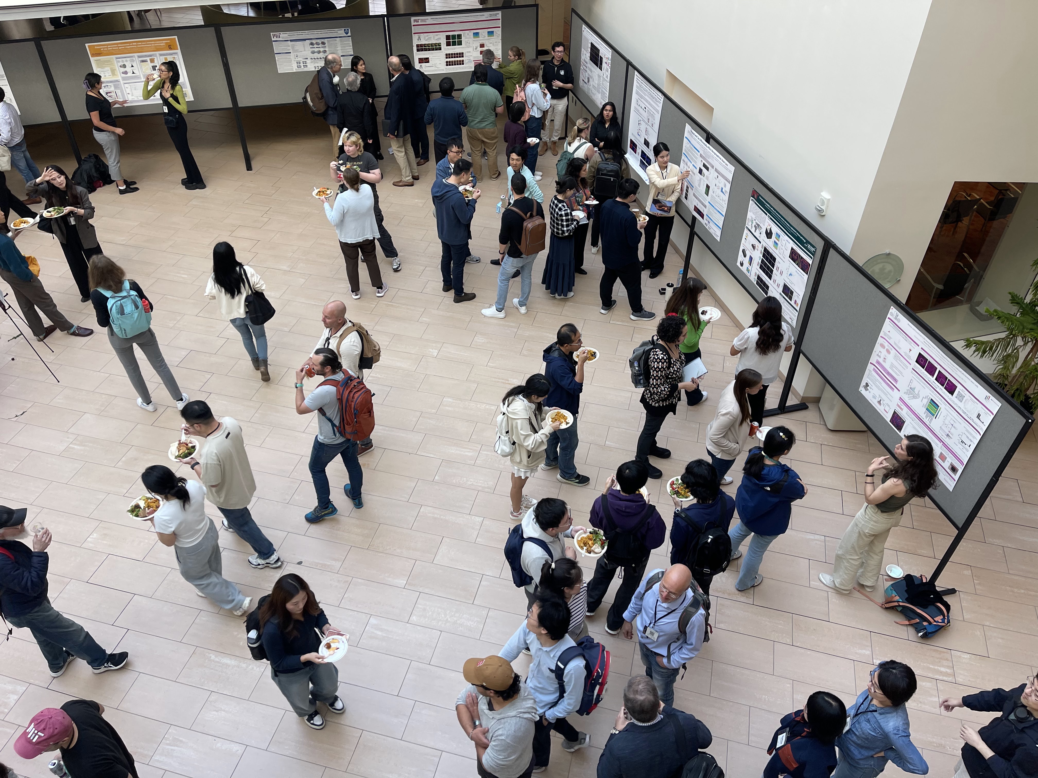An overhead view of the atrium of MIT's Building 46 shows crowds milling about a poster session.
