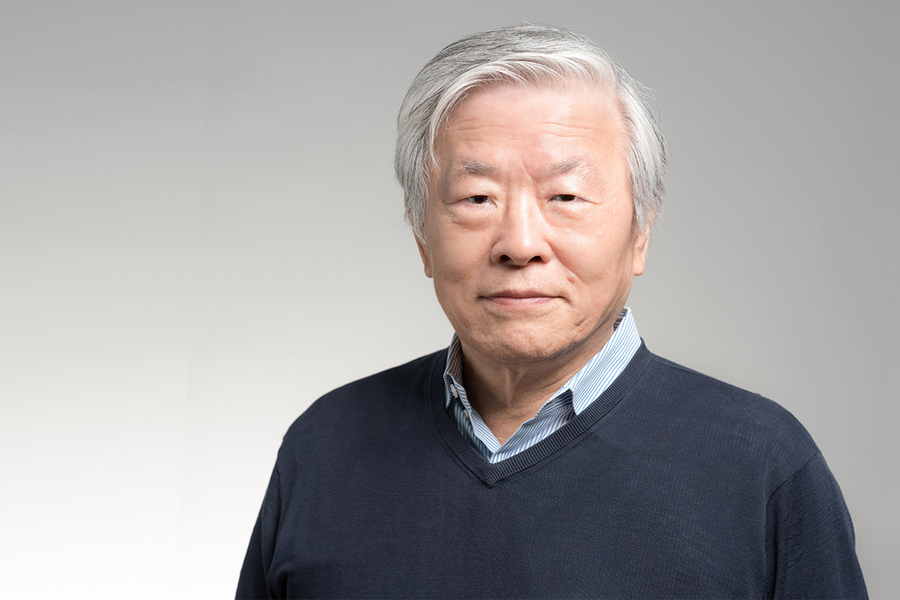 A portrait of Susumu Tonegawa in front of a gray background