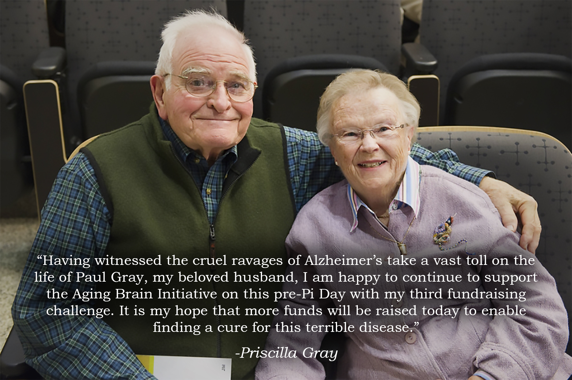 Paul and Priscilla Gray sit in adjacent seats in a lecture hall. Overlaid is a quote saying, "Having witnessed the cruel ravages of Alzheimer’s take a vast toll on the life of Paul Gray, my beloved husband, I am happy to continue to support the Aging Brain Initiative on this pre-Pi Day with my third fundraising challenge. It is my hope that more funds will be raised today to enable finding a cure for this terrible disease.”