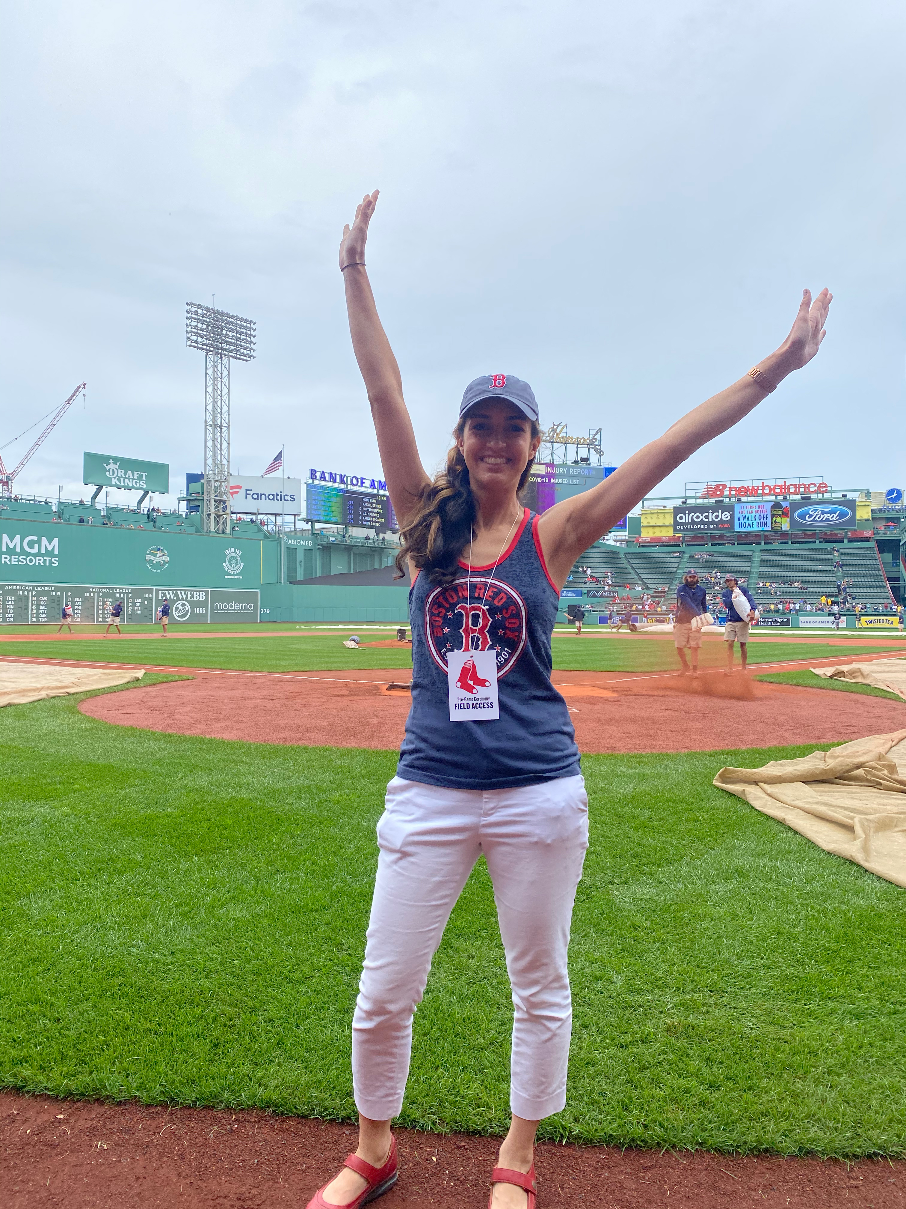 Izbella Pena stands, arms raised joyfully, behind the plate at Fenway Park