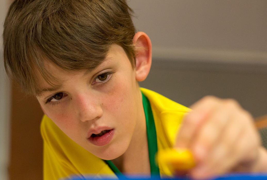 A boy in a yellow shirt plays witha toy in the foreground