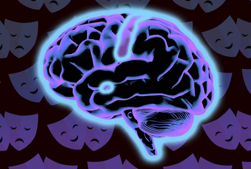 A black brain shown in a side view glows blue. The amygdala, a small almond-shaped structure toward the bottome center stands out especially. In the background there are theater masks signifying emotions.