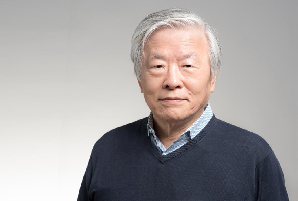 A portrait of Susumu Tonegawa in front of a gray background