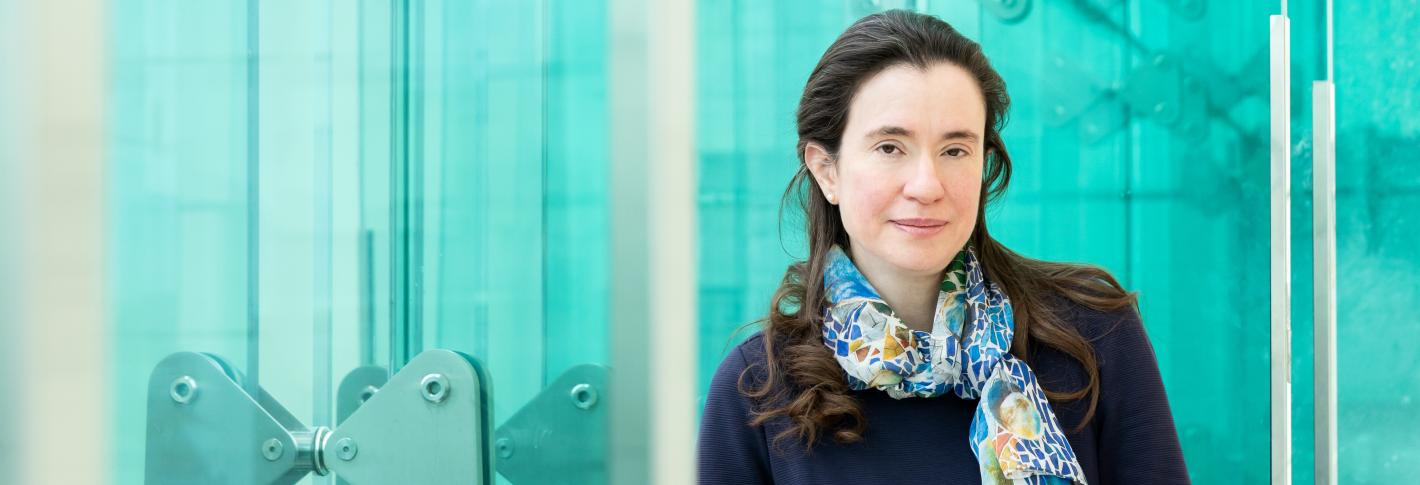 Myriam Heiman stands along the blue glassy windows of the Reading Terrace in MIT's Building 46