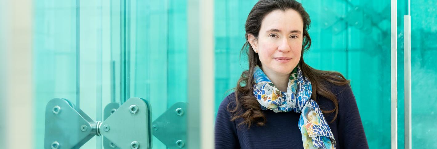 Myriam Heiman stands along the blue glassy windows of the Reading Terrace in MIT's Building 46