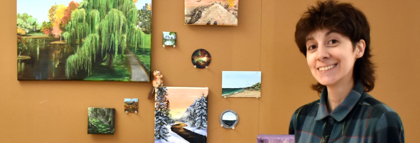 Natalie Soares stands among an array of her landscape paintings, which range in subject from wintry to desert and in size.