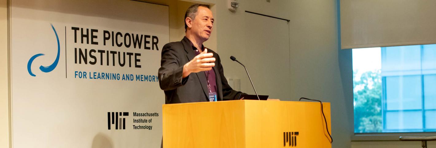 Matthew Wilson stands at an MIT podium with the Picower Institute logo behind him
