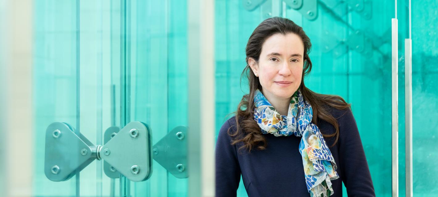 Myriam Heiman stands along the blue glassy windows of the Reading Terrace in MIT's Building 46