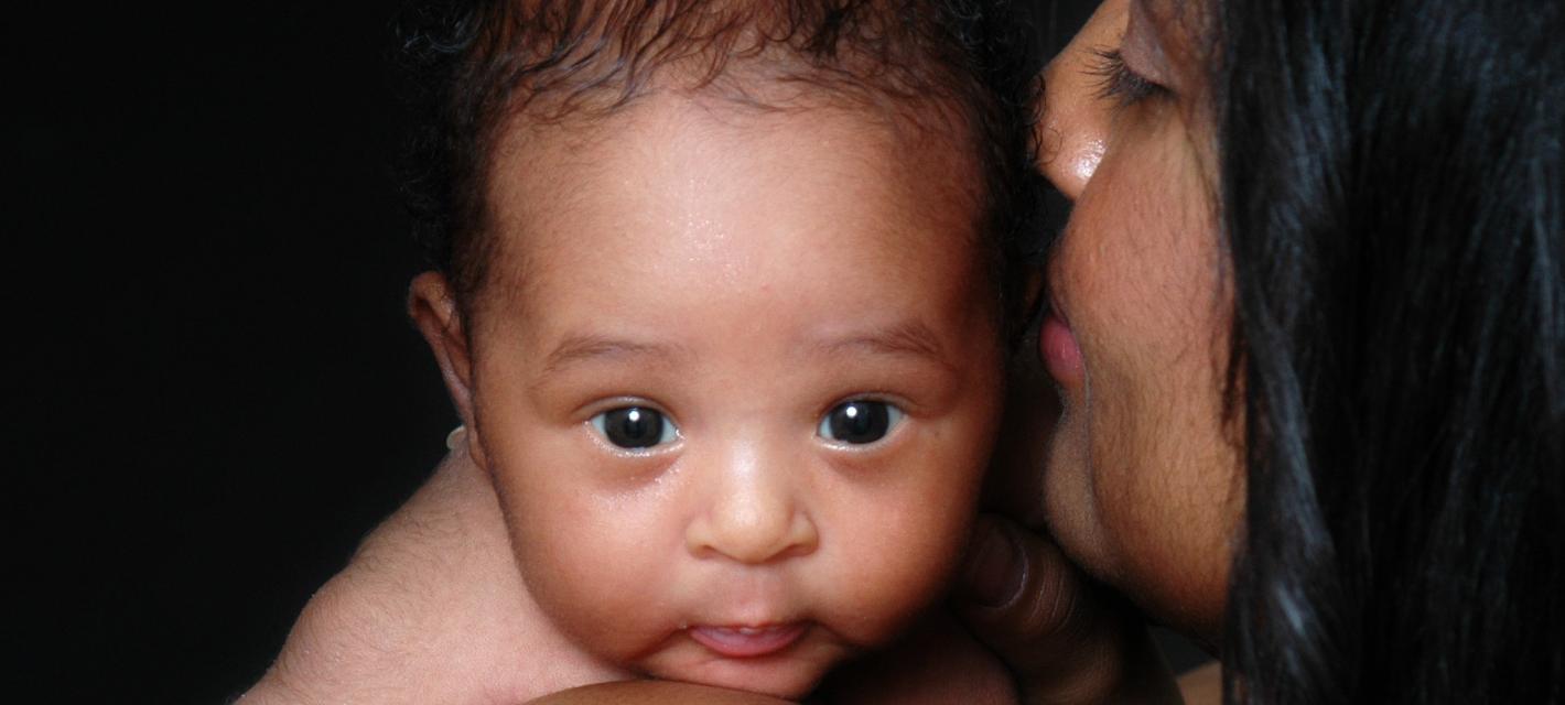 A baby looks over his mother's shoulder
