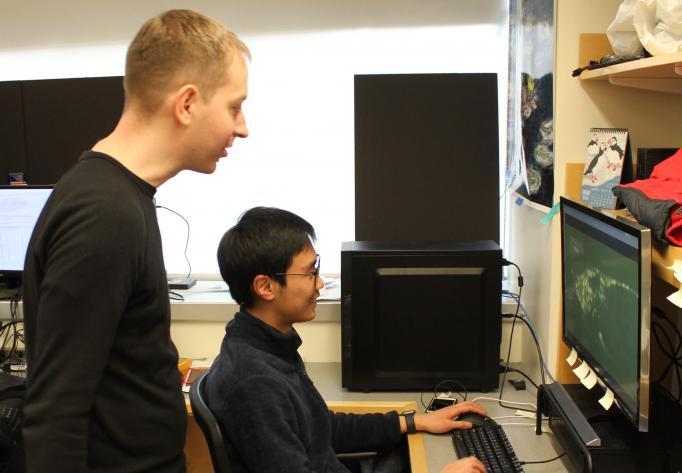 In the lab, Steve Flavell stands behind a student who displays an image on a computer screen