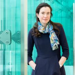 Myriam Heiman stands along the blue glassy windows of the Reading Terrace in MIT's Building 46