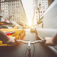A point of view of a cyclist on a busy manhattan street with a van an taxi alongside the bike
