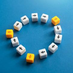 White blocks are arranged in a circle on a blue background. Black arrows on the blocks follow the direction of the circle (clockwise). At three points along the circle, yellow blocks intercede with arrows pointing outward from the circle of white blocks.