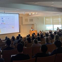 A packed auditorium looks on as Li-Huei Tsai presents a slide