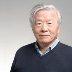 A portrait of Susumu Tonegawa in front of a gray background