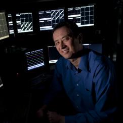 Matt Wilson sits before a bank of monitors showing readouts of neural data