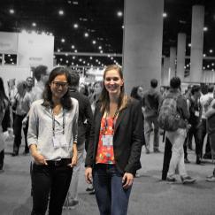 Two picower researchers are highlighted in color before a backdrop of the conference show floor, which is blurred and grayscale