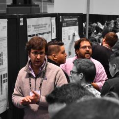 Several scientists stand before posters explaining them to onlookers